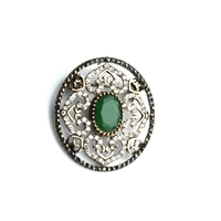 Okrągła broszka z zielonym kamieniem w centrum